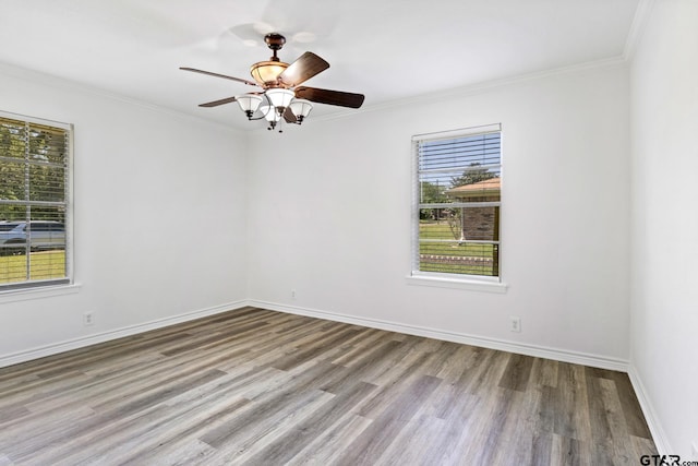 spare room with wood finished floors, ceiling fan, baseboards, and ornamental molding