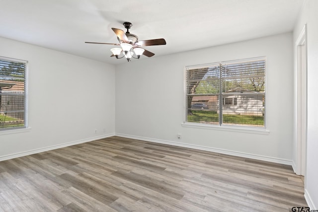 unfurnished room featuring a wealth of natural light, a ceiling fan, wood finished floors, and baseboards