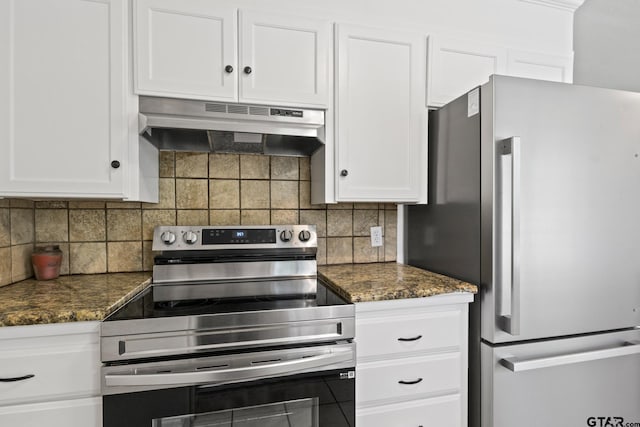 kitchen with tasteful backsplash, dark stone countertops, white cabinetry, under cabinet range hood, and appliances with stainless steel finishes