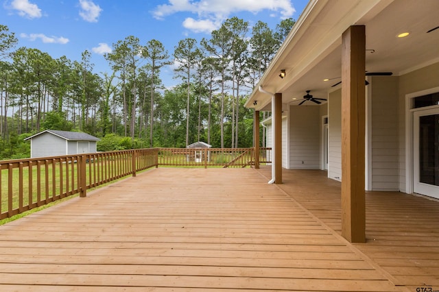 wooden deck with an outbuilding, ceiling fan, and view of scattered trees