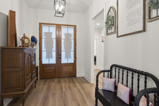 entryway featuring french doors, light wood-type flooring, and a notable chandelier