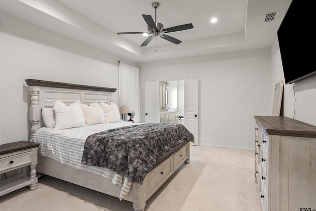 carpeted bedroom with a raised ceiling and ceiling fan