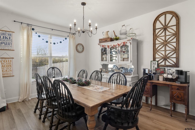 dining area with light hardwood / wood-style floors and an inviting chandelier