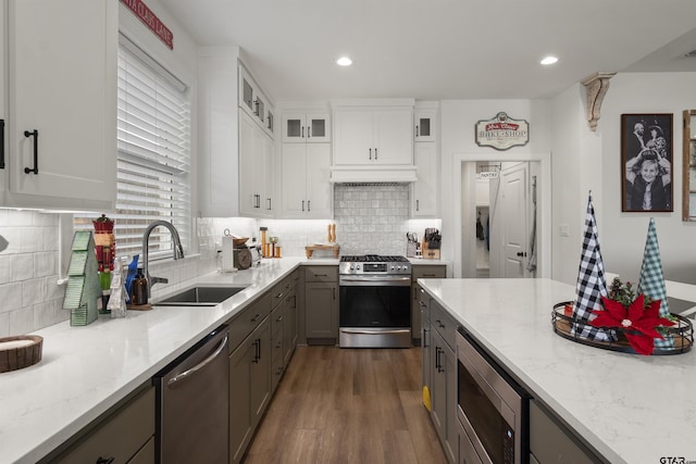 kitchen with sink, light stone counters, gray cabinets, white cabinets, and appliances with stainless steel finishes