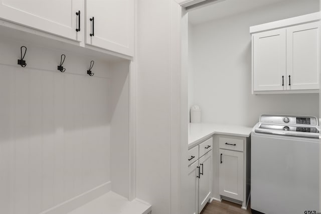 clothes washing area featuring cabinets, washer / dryer, and dark wood-type flooring