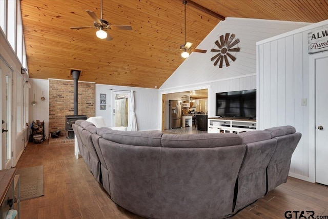 living room featuring wood-type flooring, a wood stove, wood ceiling, and ceiling fan