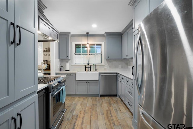 800 Neches Dr, Tyler, TX 75702 - kitchen with stainless steel appliances, gray cabinetry, light wood finished floors, light countertops, and tasteful backsplash