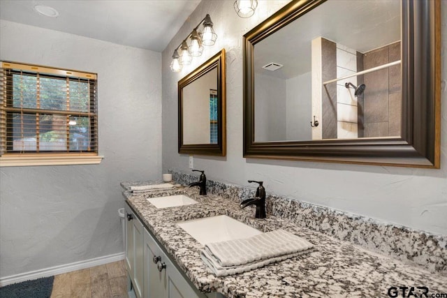 800 Neches Dr, Tyler, TX 75702 - bathroom with double vanity, wood finished floors, a tile shower, and a textured wall
