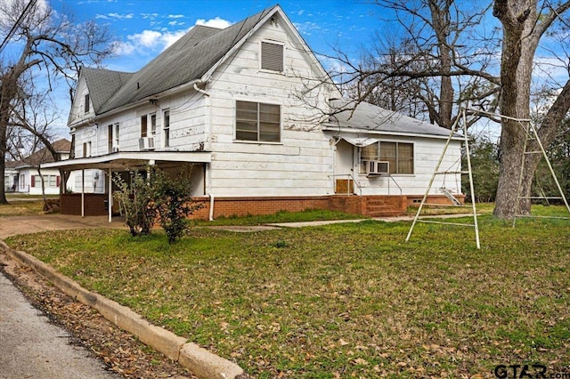 view of front facade with cooling unit, a front yard, and a carport