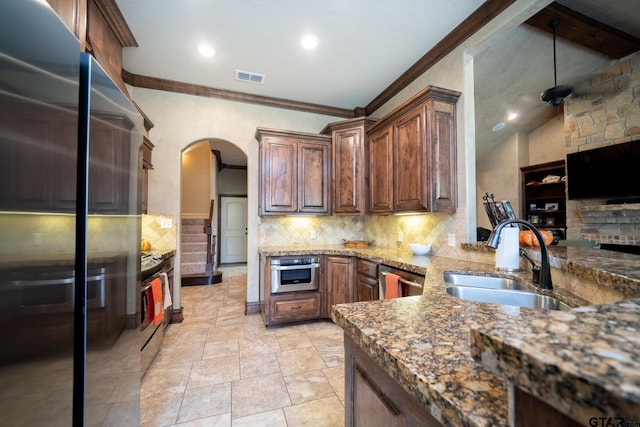 kitchen with sink, stainless steel appliances, dark stone countertops, crown molding, and light tile patterned flooring