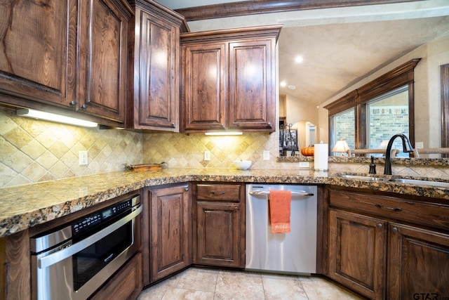 kitchen featuring light stone countertops, appliances with stainless steel finishes, tasteful backsplash, and sink