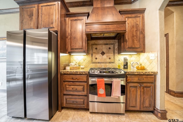 kitchen with custom range hood, backsplash, stainless steel appliances, and light stone counters