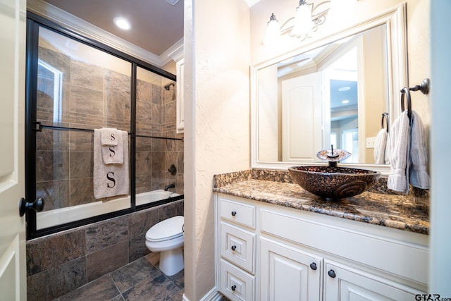 full bathroom with combined bath / shower with glass door, vanity, toilet, and ornamental molding