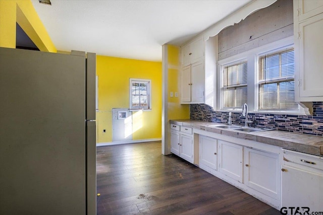 kitchen with stainless steel refrigerator, white cabinetry, sink, backsplash, and dark wood-type flooring