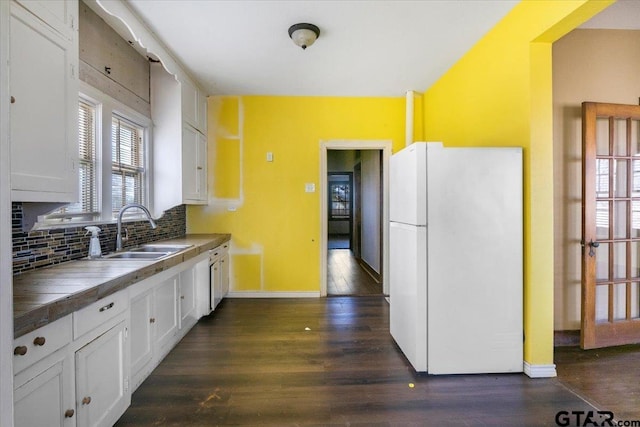 kitchen with sink, white refrigerator, white cabinets, dark hardwood / wood-style flooring, and decorative backsplash