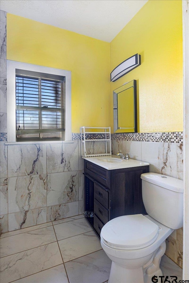 bathroom with tile walls, vanity, and toilet