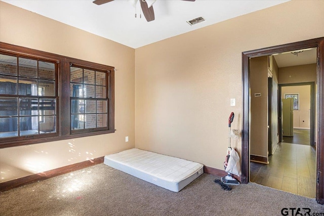 unfurnished bedroom with ceiling fan and dark carpet