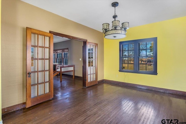 unfurnished dining area featuring a notable chandelier, dark hardwood / wood-style floors, and french doors