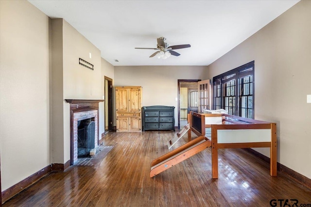 office area with a fireplace, dark wood-type flooring, and ceiling fan