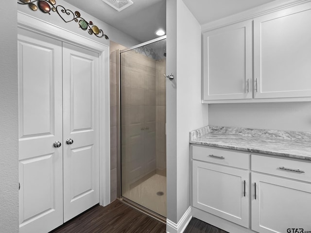 full bath featuring a stall shower, visible vents, wood finished floors, and vanity