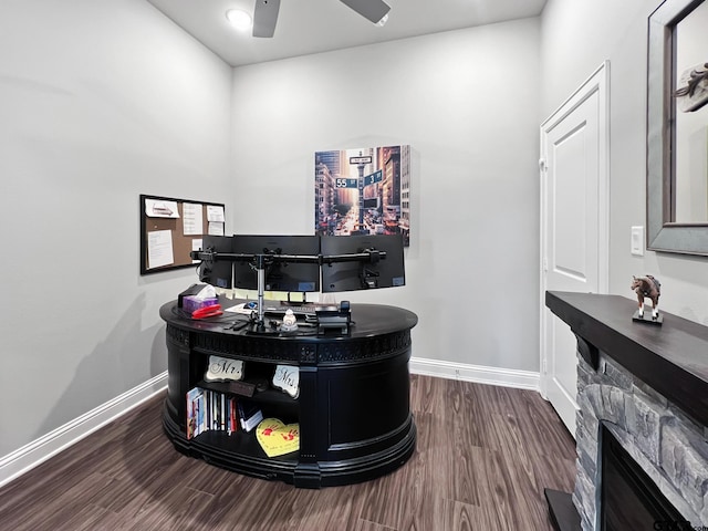 office area with a ceiling fan, a fireplace, dark wood finished floors, and baseboards