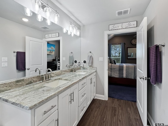 ensuite bathroom with connected bathroom, visible vents, a sink, and wood finished floors