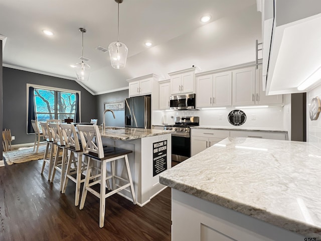 kitchen featuring a breakfast bar area, appliances with stainless steel finishes, dark wood-type flooring, white cabinetry, and backsplash