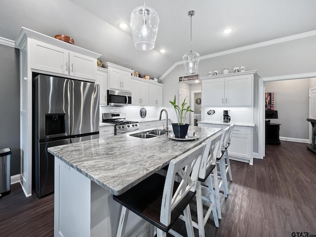 kitchen with decorative light fixtures, white cabinetry, sink, stainless steel appliances, and a center island with sink