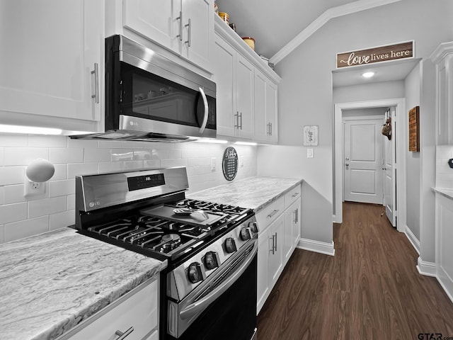 kitchen featuring appliances with stainless steel finishes, light stone counters, white cabinets, dark hardwood / wood-style flooring, and vaulted ceiling