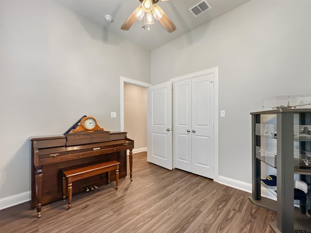 living area with visible vents, ceiling fan, baseboards, and wood finished floors