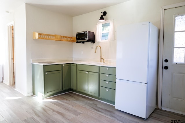 kitchen featuring light wood-type flooring, sink, white fridge, and plenty of natural light