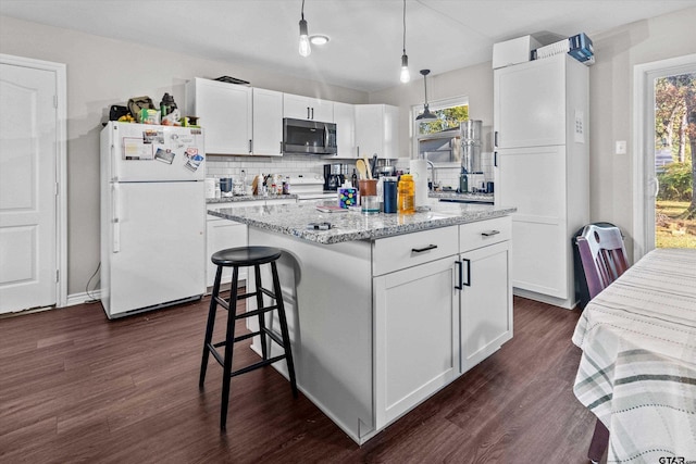 kitchen with a center island, dark hardwood / wood-style floors, decorative light fixtures, white appliances, and white cabinets