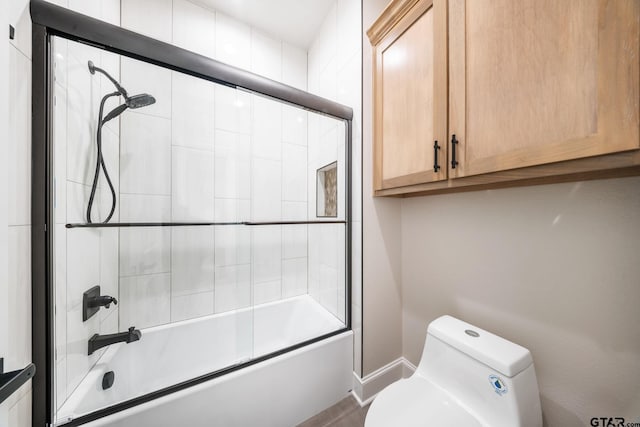 bathroom with bath / shower combo with glass door and toilet