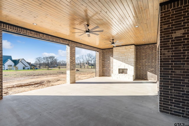 view of patio / terrace featuring ceiling fan and an outdoor stone fireplace