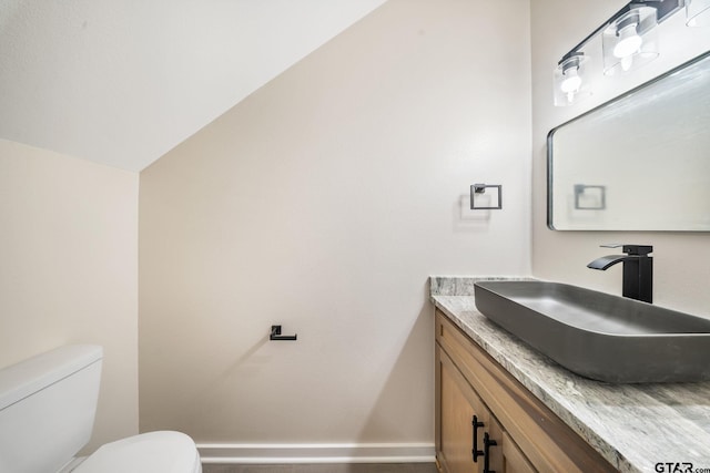 bathroom with toilet, lofted ceiling, and vanity