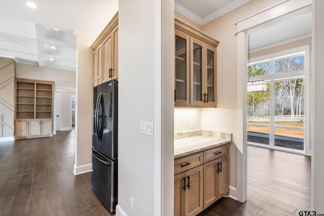 kitchen featuring black refrigerator, beam ceiling, light stone countertops, dark wood-type flooring, and crown molding