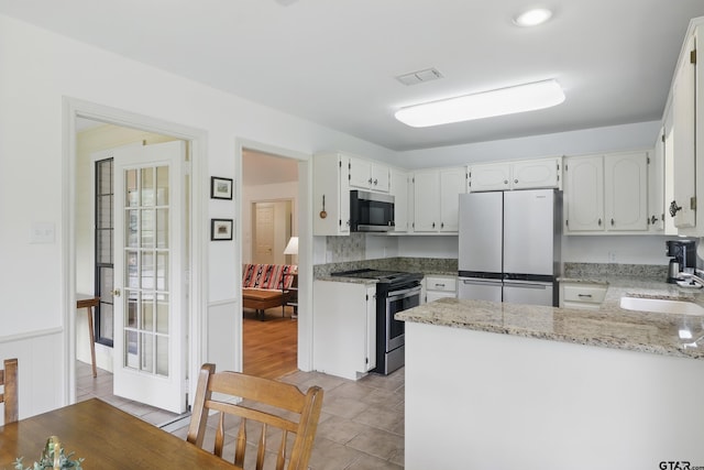 414 Winding Ln, Mount Vernon, TX 75457 - kitchen with stainless steel appliances, a peninsula, light stone countertops, and white cabinetry