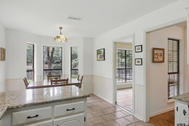 414 Winding Ln, Mount Vernon, TX 75457 - kitchen with healthy amount of natural light, white cabinets, pendant lighting, a peninsula, and a wainscoted wall