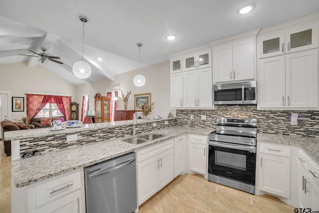 kitchen with appliances with stainless steel finishes, open floor plan, a peninsula, white cabinetry, and a sink