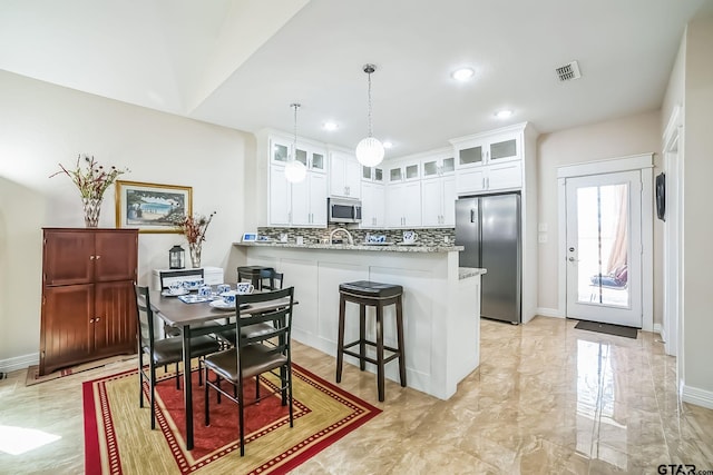 kitchen featuring visible vents, a peninsula, marble finish floor, stainless steel appliances, and backsplash