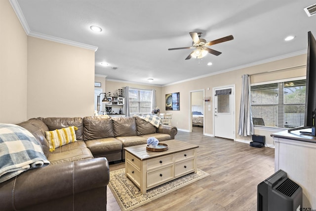 living room with visible vents, baseboards, a ceiling fan, light wood-type flooring, and crown molding