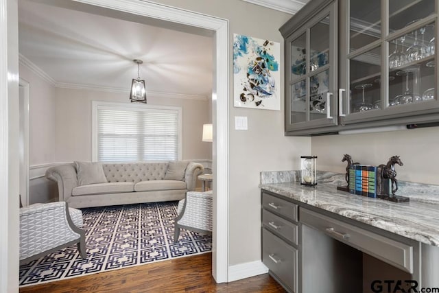 bar with gray cabinetry, pendant lighting, dark wood-type flooring, ornamental molding, and light stone counters