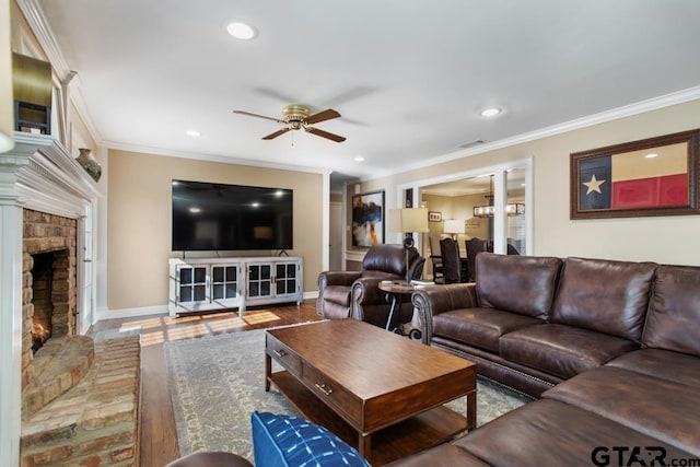 living room featuring crown molding, a fireplace, wood-type flooring, and ceiling fan with notable chandelier