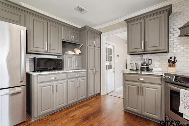 kitchen featuring stove, ornamental molding, dark wood-type flooring, gray cabinets, and stainless steel refrigerator