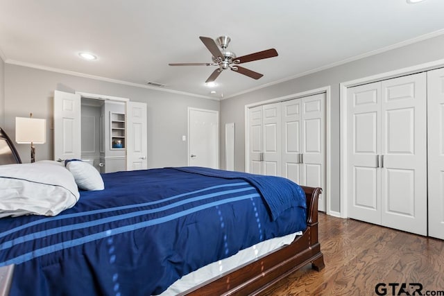 bedroom with two closets, ceiling fan, dark hardwood / wood-style floors, and ornamental molding