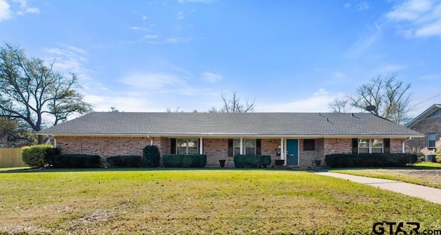 ranch-style house featuring brick siding, a shingled roof, and a front yard