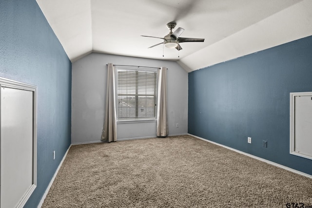 carpeted empty room with baseboards, vaulted ceiling, and a ceiling fan