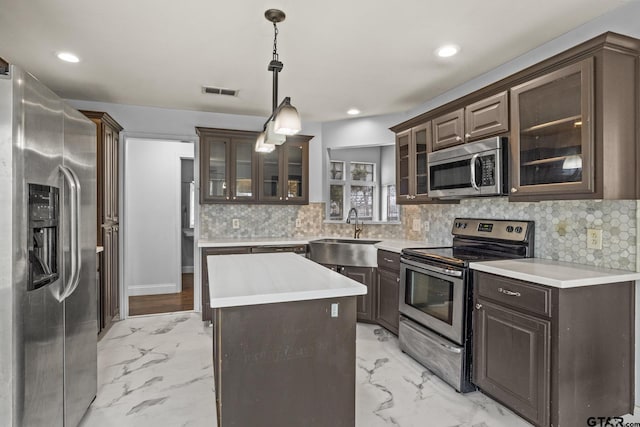 kitchen featuring stainless steel appliances, light countertops, glass insert cabinets, and a sink