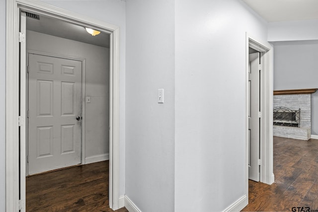 hall featuring visible vents, baseboards, and dark wood finished floors