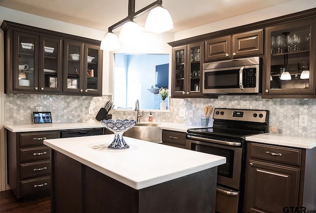 kitchen with decorative light fixtures, a kitchen island, sink, dark brown cabinetry, and stainless steel appliances